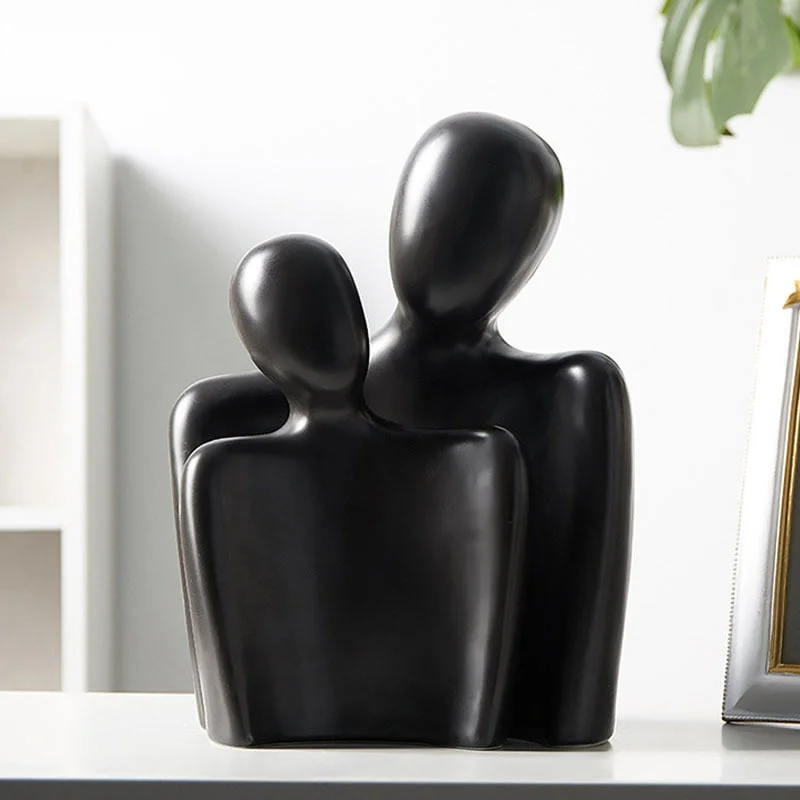 Black abstract two-figure sculpture next to a plant