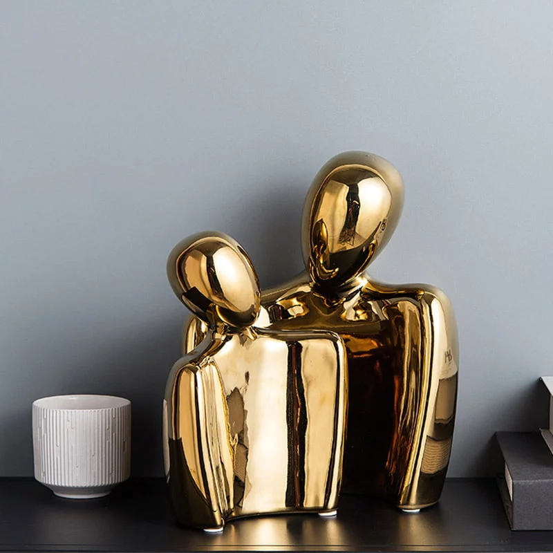 Gold finish abstract two-figure sculpture on a shelf