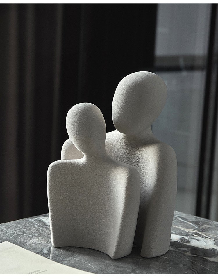 Abstract two-figure sculpture in light grey on a marble side table