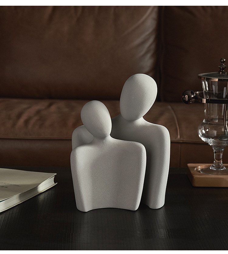 Light grey abstract sculpture styled on a dark coffee table in a living room