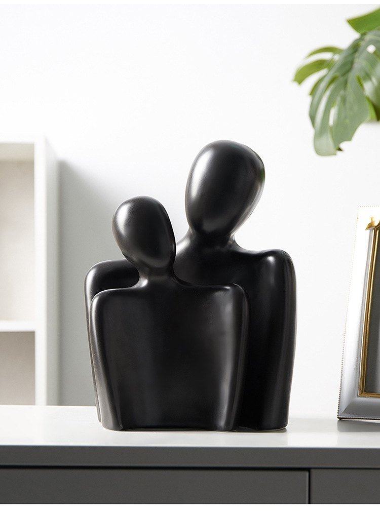 Black abstract two-figure sculpture on a white shelf