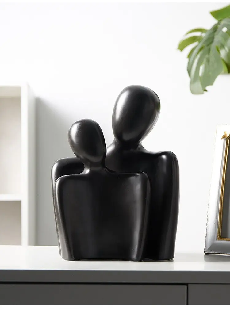 Black abstract two-figure sculpture on a white shelf
